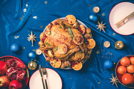 Roasted Christmas Turkey With Orange Slices, Cranberries, Garlic, Festive Decoration, Candles, Tangerine, Pomegranate, Golden Cultery, Star Glitter Sparkles. Festive Family Christmas Dinner.