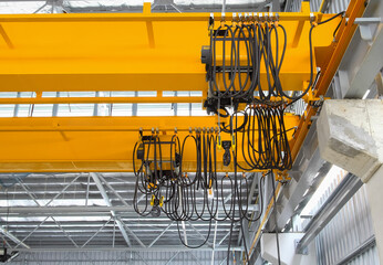 Overhead crane inside factory or warehouse. That industrial machinery or lifting equipment consist of hoist, hook and wire rope traveling on beam girder structure. For manufacturing production plant.