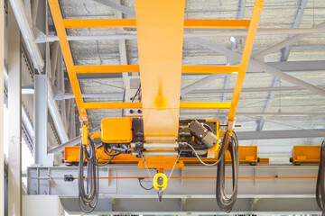 Overhead crane inside factory or warehouse. That industrial machinery or lifting equipment consist of hoist, hook and wire rope traveling on beam girder structure. For manufacturing production plant.