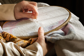 Close up woman hands doing needlework on embroidery frame. Cross stitching, hobby, diy