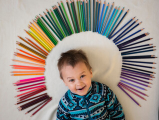 little boy lying on the floor with colored pencils, selective focus