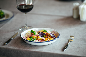 Gourmet salad with crackers and vegetables on the served table with a glass of red wine