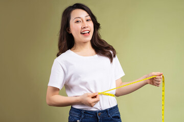 Young asian girl happily holding the tape measure after losing weight