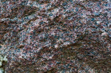 Chipped red gray granite stone close-up, beautiful texture, rough textured surface, exposure to atmosphere, outdoors.