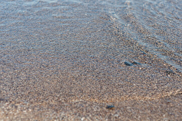 Blurred background surface sea water, view through troubled water to beautiful small pebbles, outdoors.