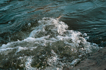 Rapids small river, strong current water flowing among stones, beautiful nature