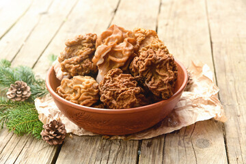 Morel mushrooms in a brown ceramic bowl on a wooden table. Outdoor. 