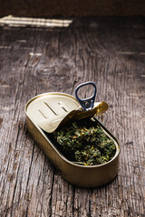 cannabis in a tin can. on old wooden background. rustic