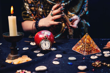 A fortune teller shuffles tarot cards, surrounded by magical and mysterious objects. Hands close-up. The concept of astrology, magic and esotericism