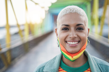 Happy gay woman wearing LGBT rainbow flag pride mask - Focus on face
