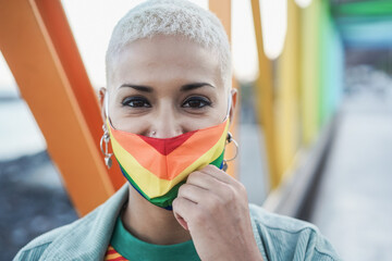 Young lesbian smiling on camera while wearing rainbow mask - Focus on face