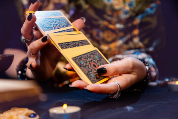 Esotiricism. The witch shuffles the tarot cards in her hands. Close-up. The concept of witchcraft and divination - obrazy, fototapety, plakaty