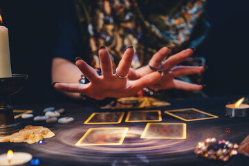 Astrology. The sorceress conjures over the tarot cards spread out on the table. Hands close-up. The concept of magic and esotericism