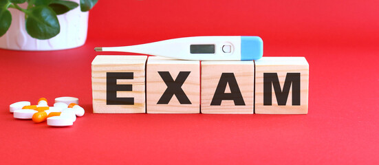 The word EXAM is made of wooden cubes on a red background. Medical concept.