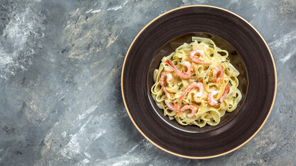Italian pasta fettuccine with grilled shrimps, bechamel sauce and thyme, fettuccine pasta. Italian food. Long banner format, top view