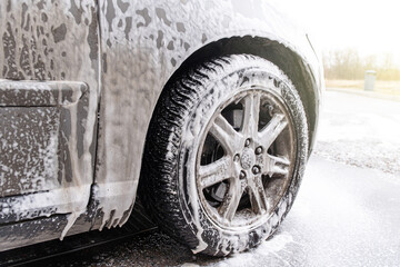 Car covered with washing foam at contactless car washing service