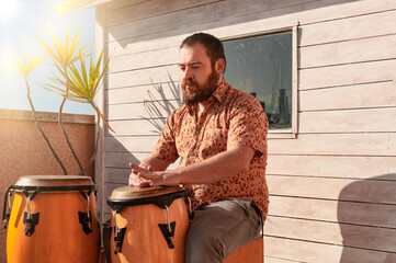 Close up of conga drums with man's hands holding drumsticks set on concrete floor in a stadium for...