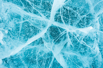 Texture of beautiful blue ice with cracks and air bubbles in the frozen lake. Winter nature background. Lake Baikal, Siberia, Russia.