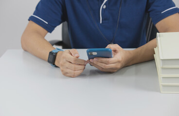 Hands of a man typing on a smartphone on a table.