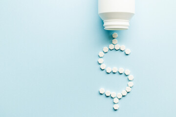 Medicine pills dollar shape with bottle on blue background. Earnings concept.