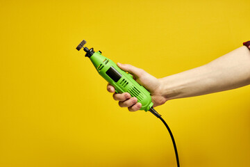Power tool. Green Die grinder in hands isolated on yellow background