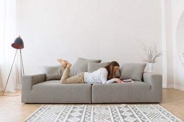 Young woman reading on the couch at home.