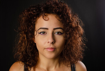 Portrait of a beautiful young Brazilian woman with brown hair, dark background, selective focus.