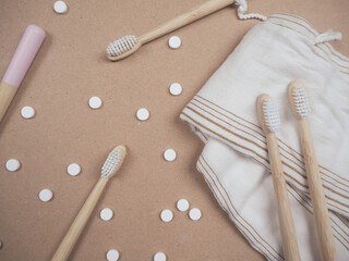 Bamboo toothbrush and dental tabs on a wooden background, plastic free swap.