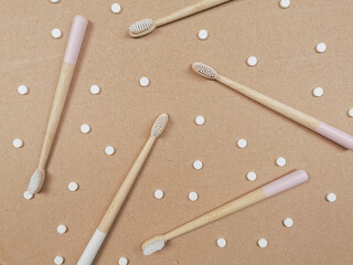 Bamboo toothbrush and dental tabs on a wooden background, plastic free swap.