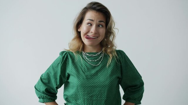 Portrait of funny young lady making playful facial expressions and grimacing on white color background. Joyful millennials and crazy activities concept.