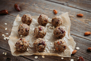 Close-up of homemade dried fruit, nuts and oatmeal balls. Energy balls on a wooden table and ingredients nearby. Vegetarian, vegan raw dessert.