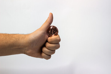 Hand holds physical bitcoin coin. Bitcoin in hand on white background. Bitcoin cryptocurrency on white canvas