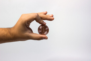 Hand holds physical bitcoin coin. Bitcoin in hand on white background. Bitcoin cryptocurrency on white canvas