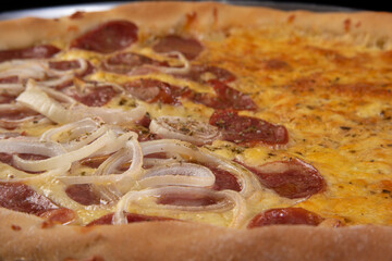 Pizza, homemade pizza half of mozzarella and half of pepperoni with onion on a table, black background, selective focus.