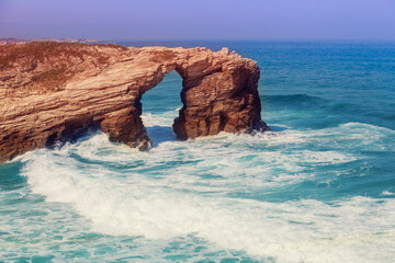 Seascape on a sunny day. Arch in the rock. Rocky sea coast on the Beach Playa de Las Catedrales. Ribadeo, Galicia, Spain