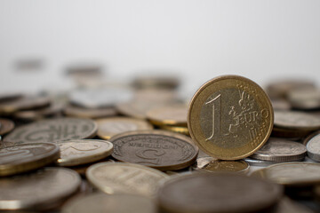 A coin worth one euro stands on other coins.
One euro against the background of other coins.