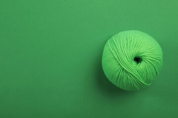 Soft woolen yarn on green background, top view. Space for text