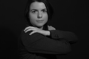 Black and white portrait of a young brunette woman in a studio on a black background