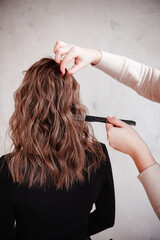 Fototapeta premium the hairdresser makes the girl styling with an iron and a comb