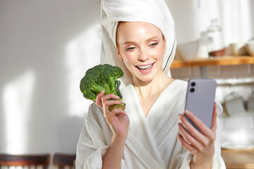 Young Caucasian Lady Holding Vegetable Broccoli Enjoying Healthy Breakfast In Modern Kitchen At Home