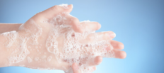 Fototapeta premium Washing female hands isolated on blue background.