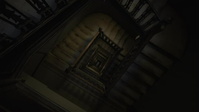 Descending top down view of old wooden staircase leading in the dark