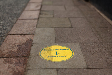 A floor sign informing the public that social distancing saves lives during the global corona virus pandemic. Covid 19 pandemic restrictions.