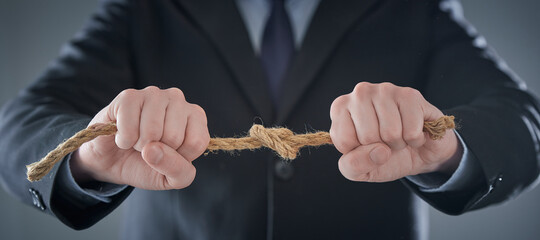 The businessman hands tighten the rope knot against background of suit in blur.