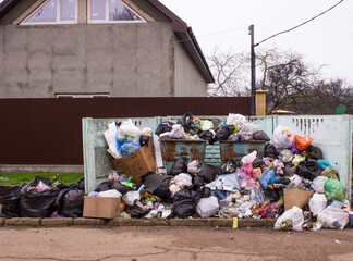 Full trash can. Trash can filled with trash. Trash can packed to overflowing with rubbish. The bin is filled with rubbish.