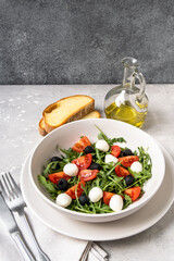 Lunch in Italian restaurant. mediterranean diet  food  salad with arugula mozzarella tomatoes and olives, olive oil and fresh bread 