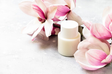 Cosmetics SPA branding mock-up. White cosmetic bottle containers with  pink magnolia flowers on...