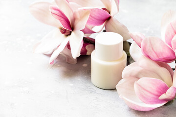 Cosmetics SPA branding mock-up. White cosmetic bottle containers with  pink magnolia flowers on gray background Natural organic beauty product concept © KEA