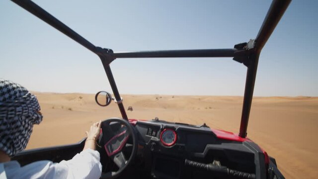 Young woman driving sand buggy on the sand dunes. Woman driving offroad vehicle in desert near Dubai
