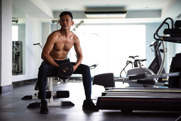 Fototapeta na wymiar Muscular bodybuilder guy lifting weights in gym.